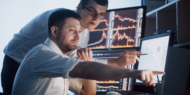 Due traders professionisti che guardano il grafico delle commissioni di Duplitrade al computer